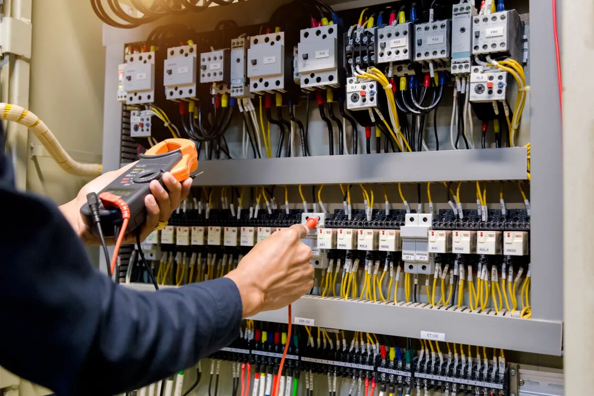 Registered electrician testing circuits in a switchboard with a clamp meter