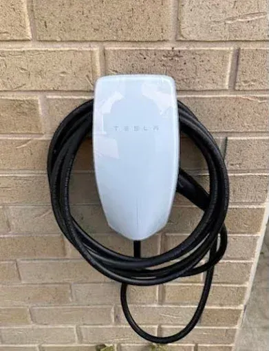 Wall-mounted home EV charger installed on a brick exterior wall